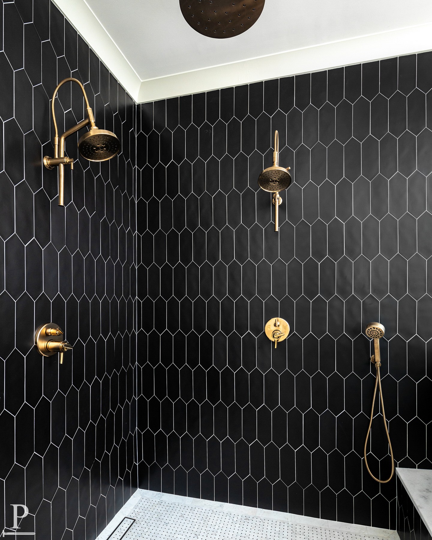 Black on black on brass.

Elongated picket tile floor-to-ceiling, dual shower systems, a ceiling-mount rain head, and white penny tile underfoot — every detail in this shower was intentional.

The contrast does the talking.