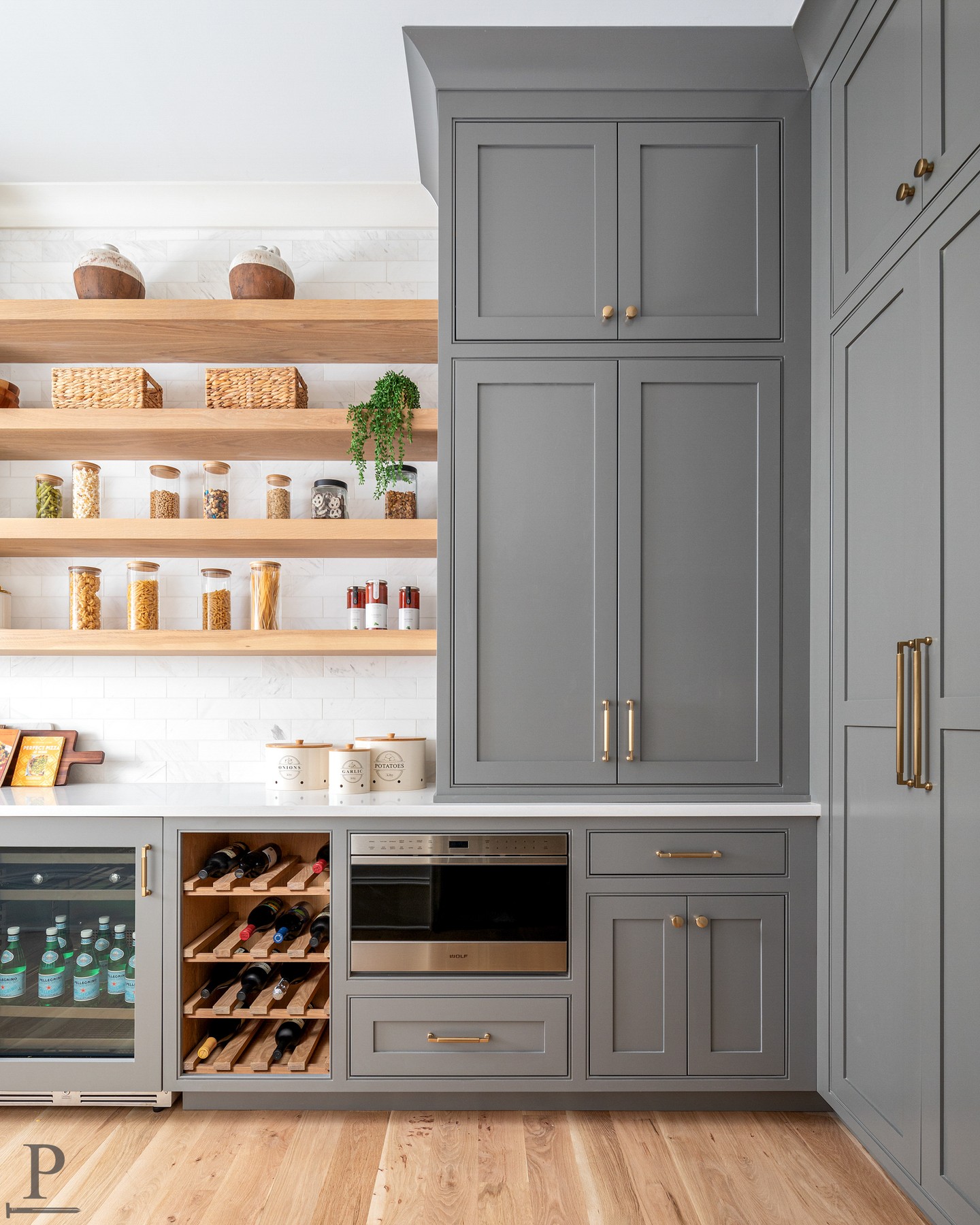 The scullery that makes the whole kitchen work.

Floor-to-ceiling cabinetry in a warm gray, open oak shelving, a built-in wine rack, beverage fridge, and a Wolf oven tucked right in. Every inch of this space has a purpose.

Swipe to see it all.