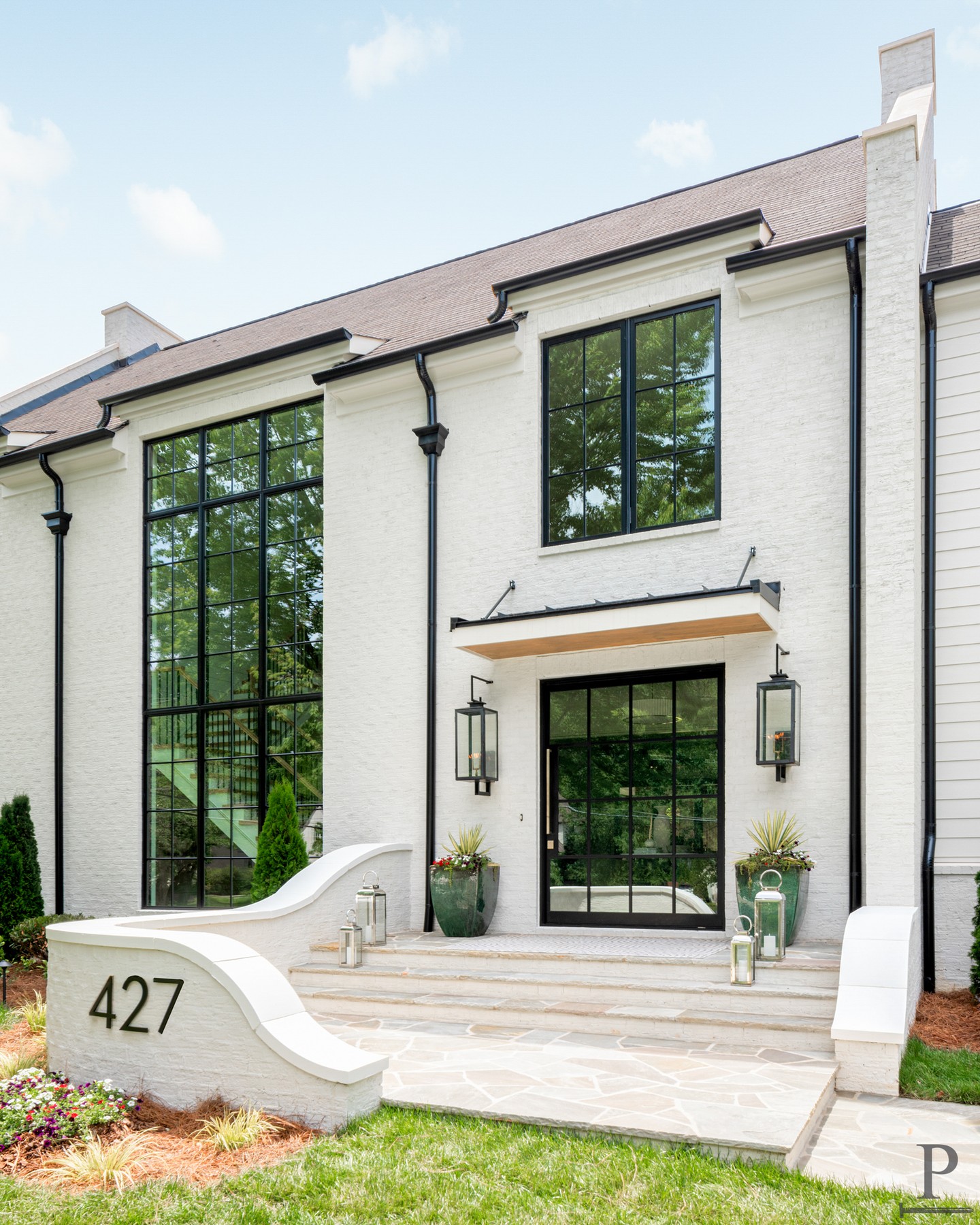 The Berkeley plan. 🌞 The kind of home that always makes us think of summer, crisp white brick, black iron windows, gas lanterns flickering, and planters spilling over with seasonal color.