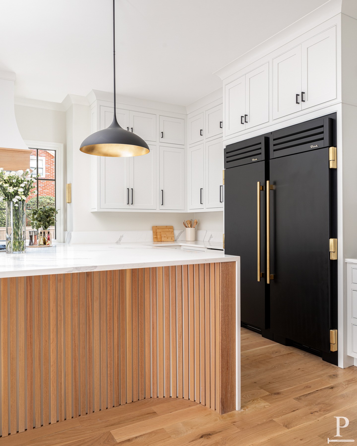 Wood tones that soften every hard edge. Matte black and brass that don't compete for attention. This Cotswold kitchen was built around contrast, done quietly.
Fluted oak on the island. A True fridge in matte black finished with brass hardware that feels more jewelry than appliance. ✨