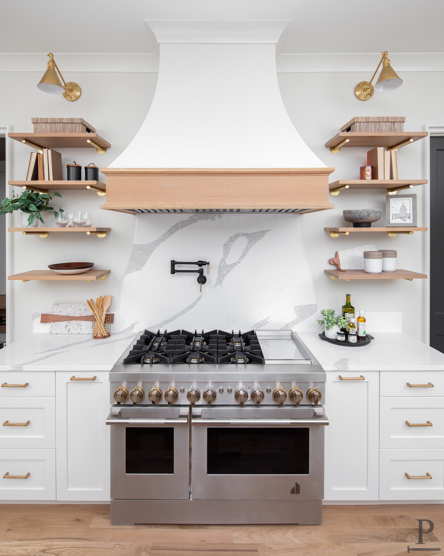 White oak, warm bronze fixtures, and cabinets in Benjamin Moore Swiss Coffee come together in this kitchen.

A range hood built to be the star, with open shelving to bring in warmth on either side.
