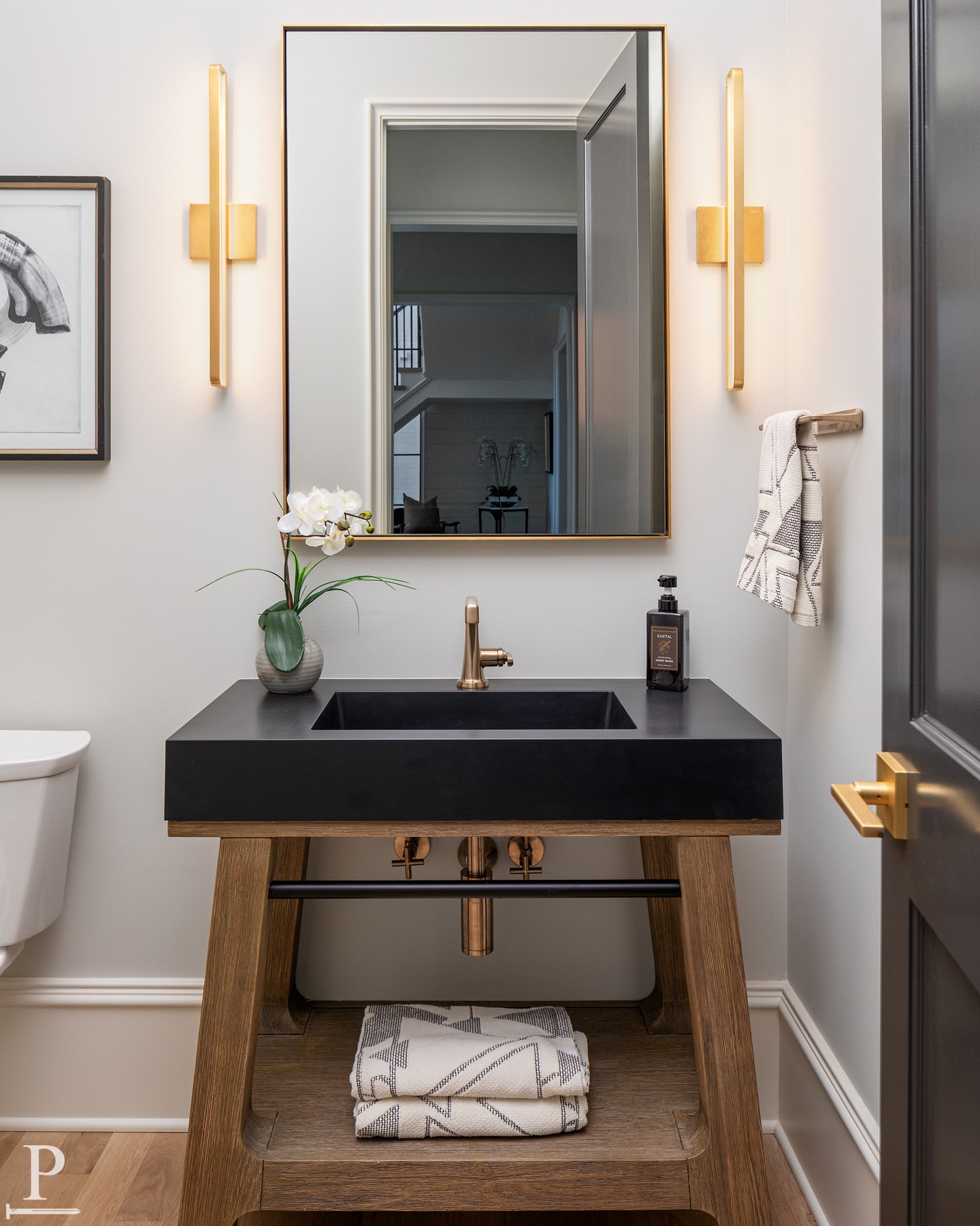 This powder bath proves small spaces can carry the most personality. A floating black stone vanity, warm brass sconces, and hardware that ties it all together without trying too hard. ✨