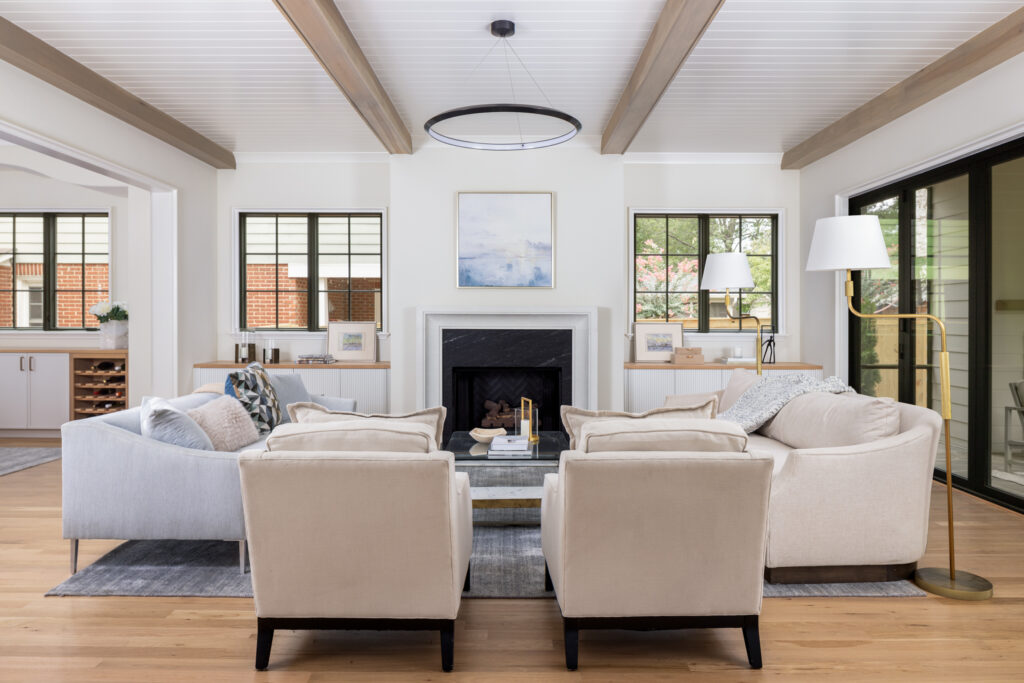 Living room with symmetrical windows flanking a fireplace, natural light, dark window grids, and warm white walls.