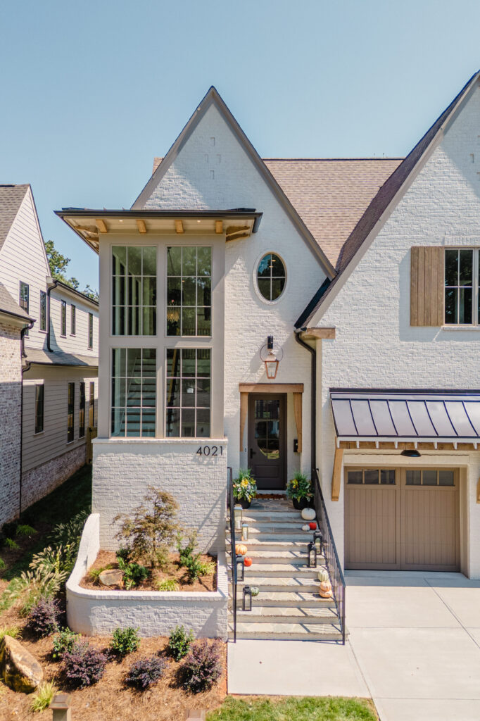 Warren plan luxury home exterior with Olympic White painted brick, wood accents, large windows, and copper gas lantern by Pike Properties in Charlotte